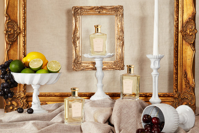 three bottles of Bouquet de la Reine surrounded by gold gilded frames and white china.