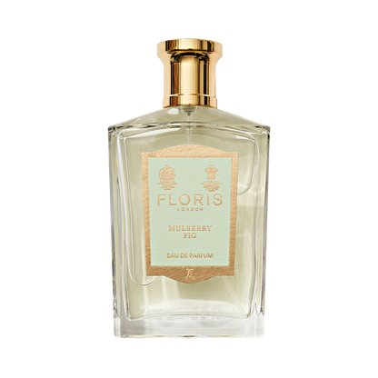 Clear glass perfume bottle with gold cap, labeled "Mulberry Fig - Eau de Parfum" by Floris London, exuding a floral amber fragrance.