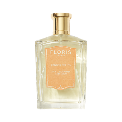 Clear perfume bottle labeled "Floris London UK, Sandalwood," featuring sandalwood oil with a gold cap and light brown label.
