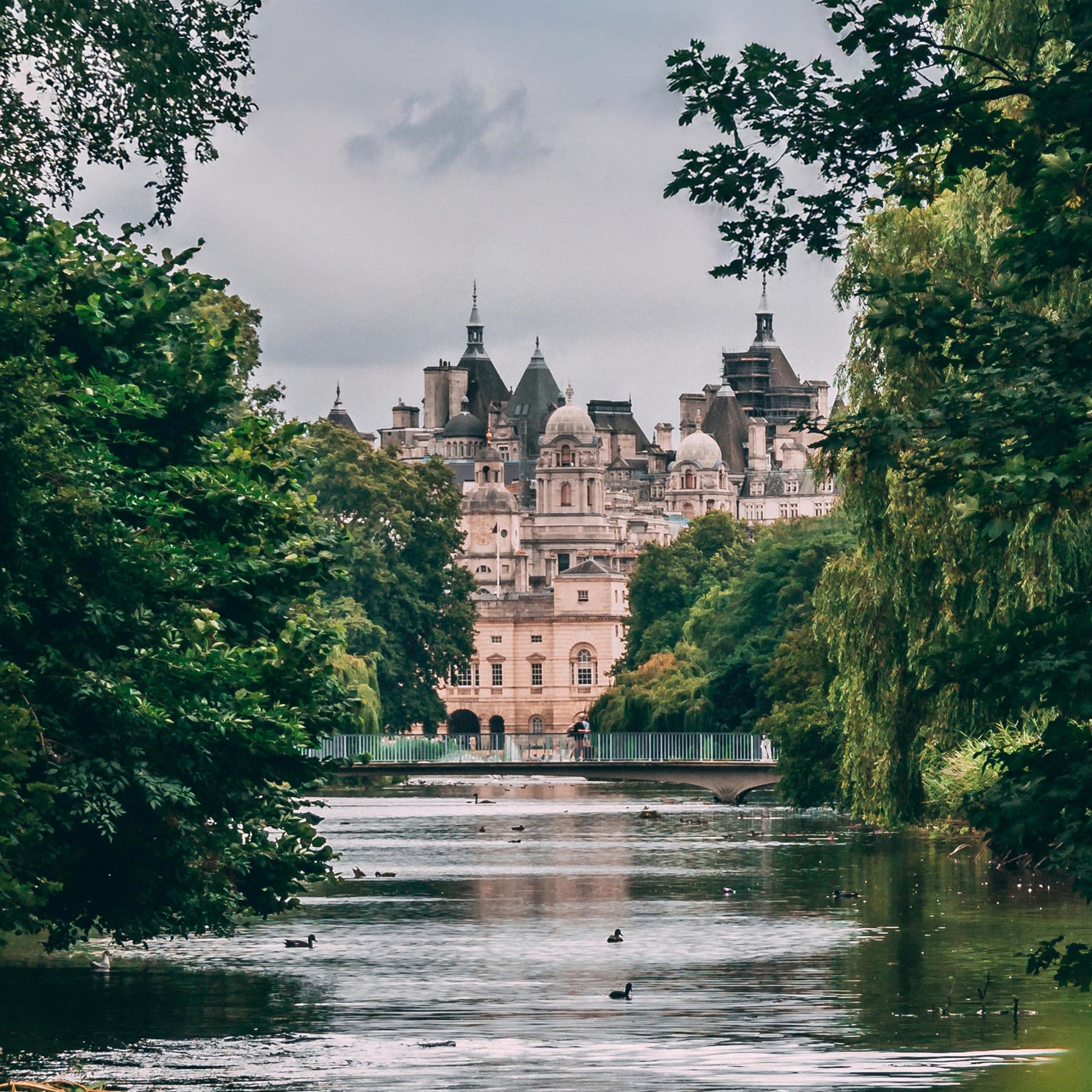 A grand historic building rises by a pond and trees as Floris London’s Mulberry Fig - Eau de Parfum scents the cloudy, duck-dotted air.